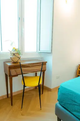 a desk with a yellow chair in a room with a bed at Quiet and cosy central apartment in Rome
