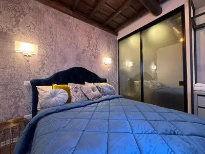 a bedroom with a blue bed and a mirror at Regina Cappellari - Elegante dimora nel cuore di Roma in Rome