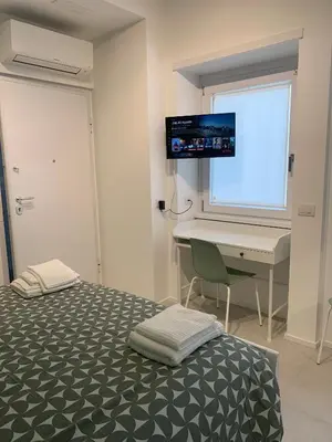 a bedroom with a bed and a desk and a monitor at Room A in Rome