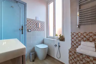 a bathroom with a toilet and a sink and a window at Orti Apartment - Charme Holidays in Rome