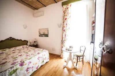 a bedroom with a bed and a table and a window at Villa Paganini B&B in Rome