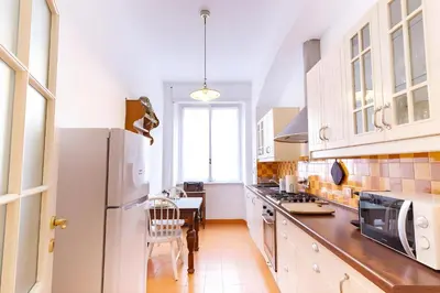 a kitchen with a white refrigerator and a table at Elegantis Solinda Suite Apartment with Private Terrace - Steps from Metro, Tram & Bus to Rome's Historic Center in Rome
