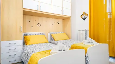 two beds in a small room with yellow curtains at Il Sogno Romano in Rome