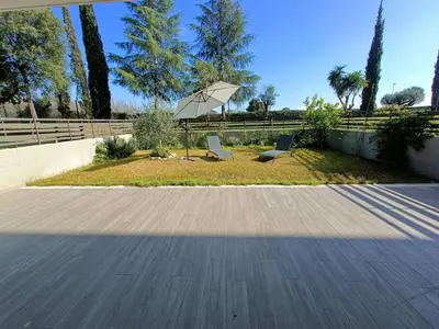 a patio with two chairs and an umbrella at Roberta and Luca cozy apartment with garden, terrace and pool in Rome