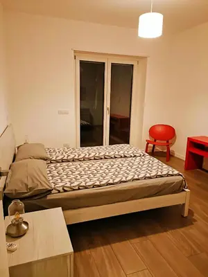 a bedroom with a bed and a red chair at Roberta and Luca cozy apartment with garden, terrace and pool in Rome