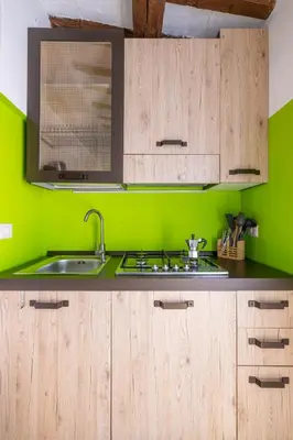 a green kitchen with wooden cabinets and a sink at Fascinating attic - up to 2 guests - Trastevere in Rome