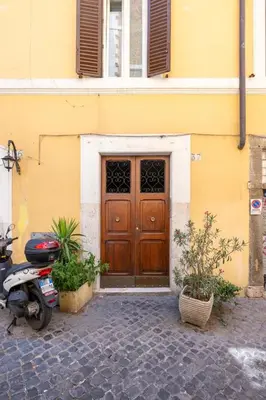 a scooter parked in front of a building with a door at Fascinating attic - up to 2 guests - Trastevere in Rome