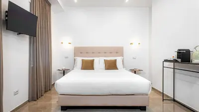 a bedroom with a white bed and a flat screen tv at Aura Vatican Suite in Rome