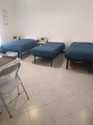 a room with three beds and a table and chairs at Teresa Amor INN Roma in Rome