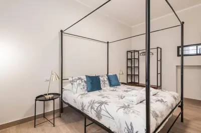 a bedroom with a black canopy bed with blue pillows at Appartamento fino a 17 persone in centro a 17 minuti a piedi da Piazza di Spagna in Rome