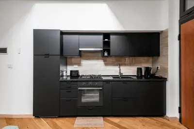 a black kitchen with a stove and a refrigerator at The Spiral Way - Trastevere apartment with large private terrace in Rome