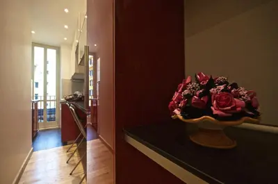a vase of red roses on a counter in a room at Piramide House in Rome