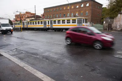 a red car driving down a street with a train at ad duas lauros in Rome