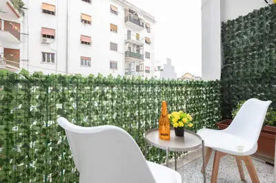 a balcony with white chairs and a table and a green wall at Domvs Clavdia - 7min to Colosseum by Metro, Station under apt, Roma, 6pax, A-C in Rome
