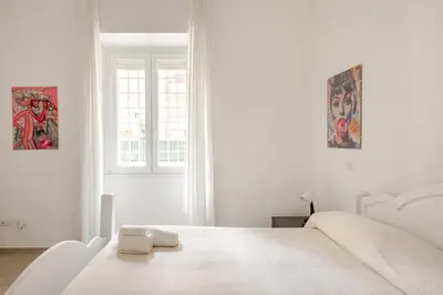 a white bedroom with a white bed and a window at Casa Polly in Rome