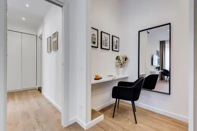 a white hallway with a black chair and a mirror at Scipioni Luxury Apartment in Rome