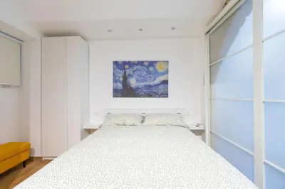 a white bedroom with a bed and a painting at Troppo Forte appartamento a due passi dal Colosseo in Rome
