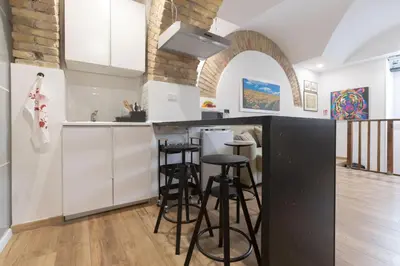 a kitchen with white cabinets and bar stools at Troppo Forte appartamento a due passi dal Colosseo in Rome