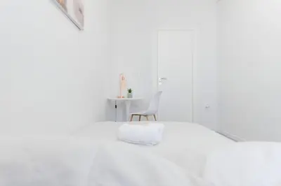 a white bedroom with a white bed and a chair at 10 Min from Termini Sisters Cozy Rome Apartment in Rome