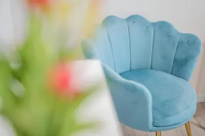 a blue chair in a room with a flower at 10 Min from Termini Sisters Cozy Rome Apartment in Rome