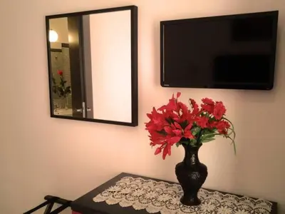 a vase with red flowers on a table with a mirror at B&B Trastevere in Bed in Rome