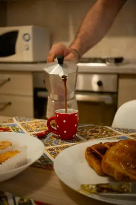 a man is pouring coffee into a red cup on a table at Appartamento Rea Silvia in Rome