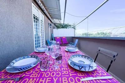 a table with plates and glasses on a pink table cloth at Escher's Penthouse on Nomentana in Rome