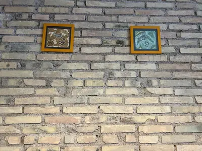 three framed pictures on a brick wall at Lilla a Testaccio in Rome