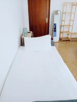 a white bed in a room with a wooden door at DOMUS REMO Room #1 in Rome