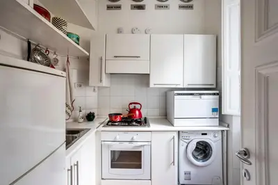 a kitchen with white cabinets and a washer and dryer at Your nest with wooden ceilings in Monti in Rome