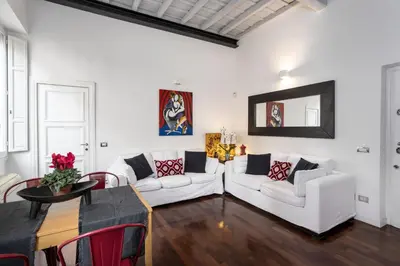 a living room with two white couches and a table at Your nest with wooden ceilings in Monti in Rome