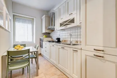 a kitchen with white cabinets and a table and chairs at BDC - Central charming 2-Bdr! in Rome