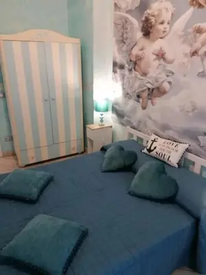 a bedroom with a blue bed with pillows and a crib at Le chat bleu in Rome