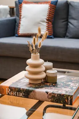 a coffee table with a vase on top of a book at DAMA APARTMENT 2 camere da letto 2 bagni con doccia in Rome