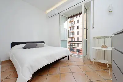 a bedroom with a white bed and a large window at Testaccio Sweet Holiday Apt in Rome
