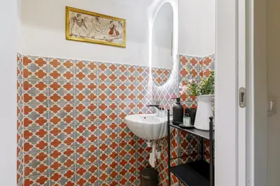 a bathroom with a sink and a tiled wall at Rome As You Feel - Charming Space at Torre Argentina in Rome