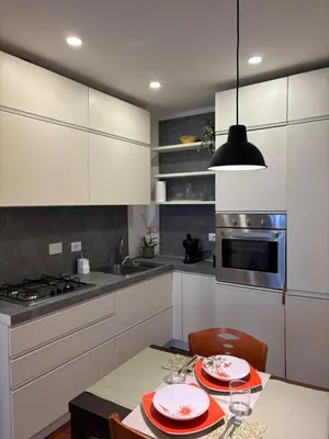 a kitchen with white cabinets and a table with plates at Gina's House Trastevere Station in Rome