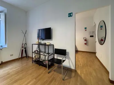 a room with a chair and a television in it at JHHIT - San Pietro First Suite in Rome
