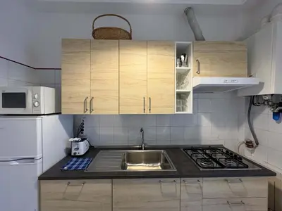 a kitchen with a sink and a stove and cabinets at JHHIT - San Pietro First Suite in Rome