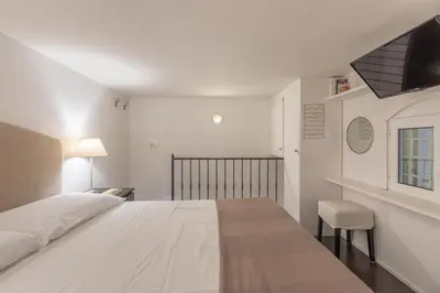 a white bedroom with a large bed and a chair at iFlat Monti Studio Apartment in Rome