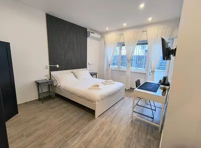 a bedroom with a bed and a desk and windows at San Pietro Experience in Rome