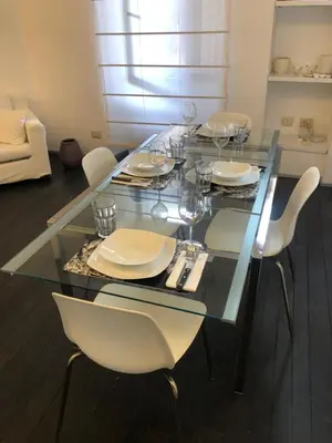 a glass table with white chairs and plates and glasses at Vatican 3th Floor in Rome