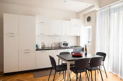 a kitchen with white cabinets and a table and chairs at ST PETER APARTMENT metro at 3 minutes in Rome