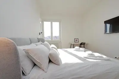 a white bed with white pillows and a window at Vatican Basilica Apartment in Rome