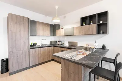 a kitchen with wooden cabinets and a black counter top at Private Parking - Bilocale Monti Tiburtini in Rome