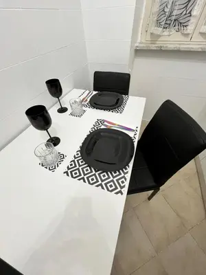 a white table with black chairs and wine glasses at Apartment Dacia Colosseum in Rome