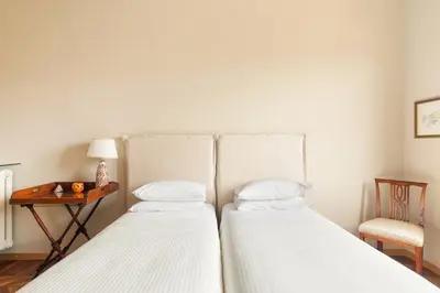 two beds in a bedroom with a table and a chair at Casa Augusta, a Burghesius home in Rome