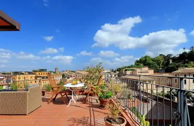 a patio with a table and chairs on a balcony at Trastevere Penthouse amazing terrace in Rome