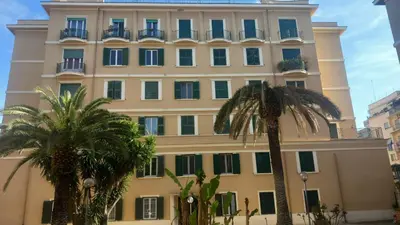 a large building with palm trees in front of it at Il regno dei colori in Rome