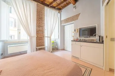 a bedroom with a bed and a kitchen with a tv at Secret Studio Retreat in the Heart of the Ghetto by Houseeds in Rome